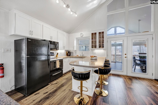 kitchen featuring a sink, white cabinets, light countertops, black appliances, and glass insert cabinets