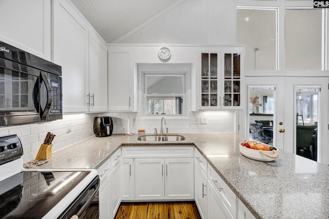 kitchen featuring range with electric stovetop, glass insert cabinets, white cabinetry, a sink, and black microwave