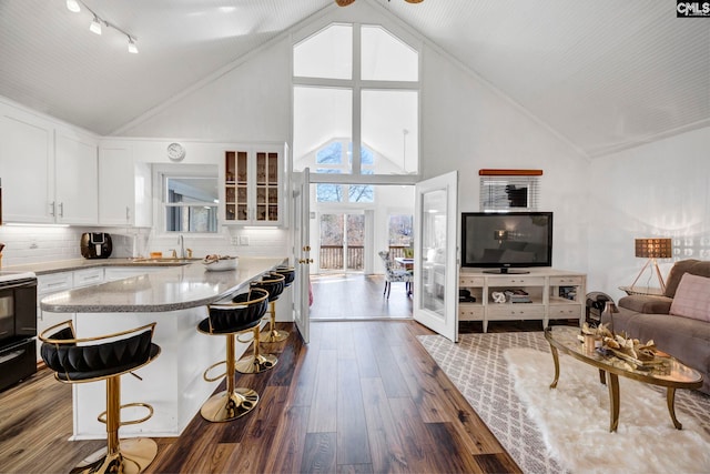 kitchen with a kitchen breakfast bar, open floor plan, white cabinets, dark wood-style floors, and glass insert cabinets