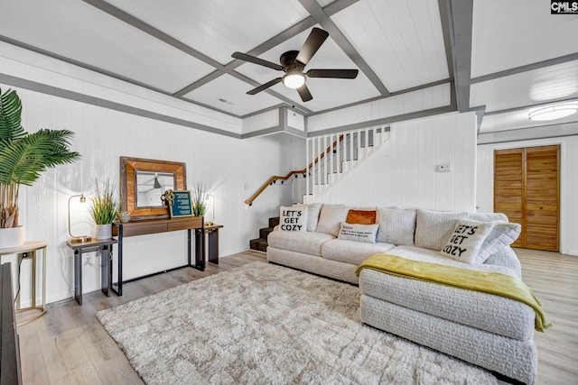 living area with stairs, ceiling fan, beamed ceiling, and light wood-type flooring