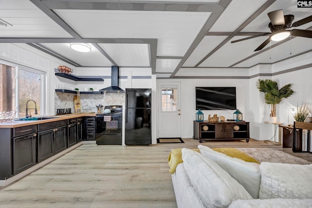 kitchen with a healthy amount of sunlight, a sink, wall chimney range hood, and black appliances