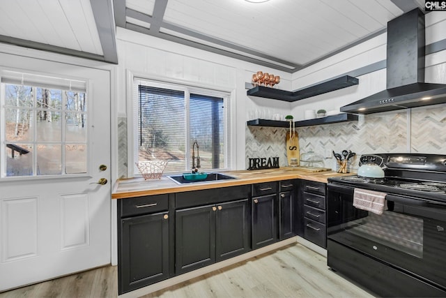 kitchen featuring wall chimney range hood, black / electric stove, wooden counters, and a sink