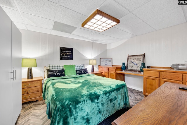 bedroom with brick floor, a drop ceiling, and built in desk