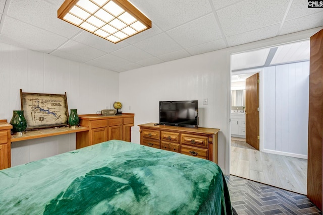 bedroom featuring brick floor and a drop ceiling