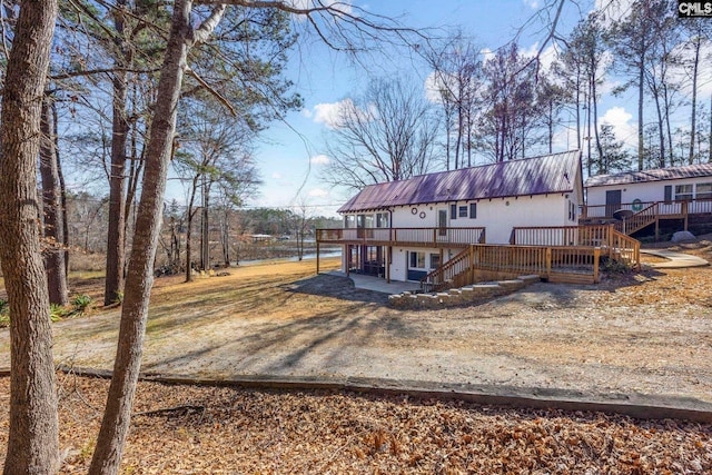 back of property featuring metal roof, stairway, and a wooden deck