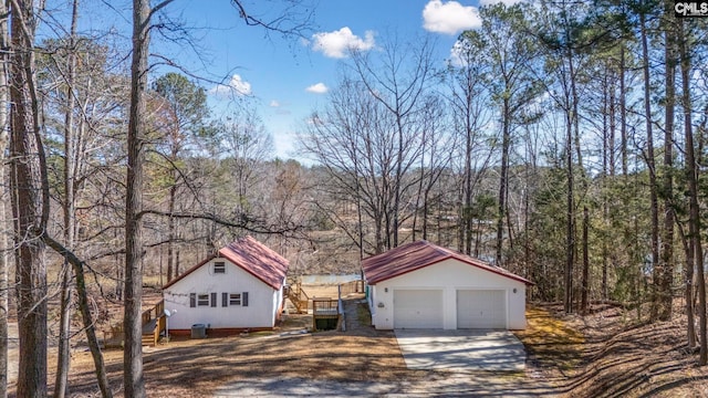 exterior space featuring a forest view, a detached garage, and an outdoor structure