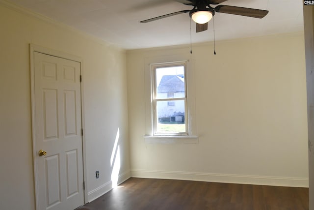 empty room with a ceiling fan, crown molding, dark wood finished floors, and baseboards