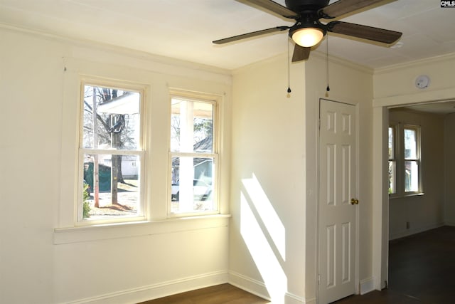 interior space with ornamental molding, plenty of natural light, a ceiling fan, and baseboards