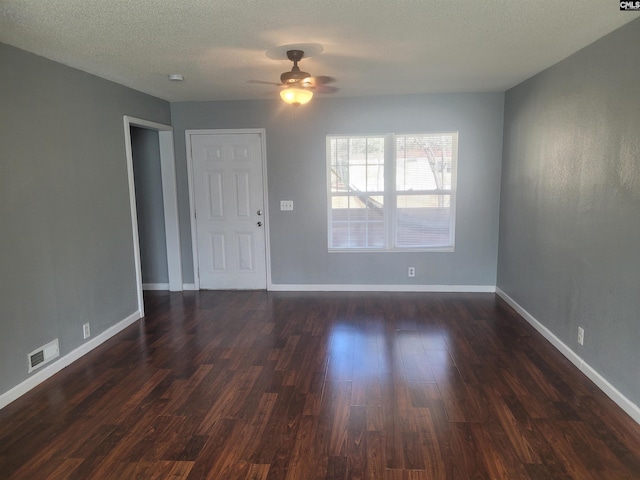 interior space featuring baseboards, visible vents, ceiling fan, dark wood-type flooring, and a textured ceiling