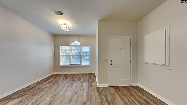 foyer entrance featuring baseboards, visible vents, and wood finished floors