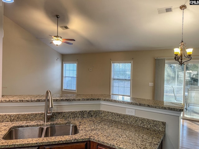 kitchen with a wealth of natural light, stone counters, visible vents, and a sink