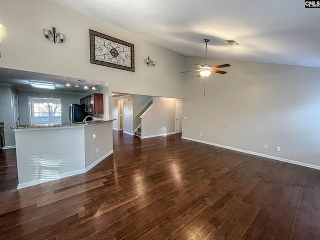 unfurnished living room featuring visible vents, ceiling fan, stairway, dark wood-style flooring, and high vaulted ceiling