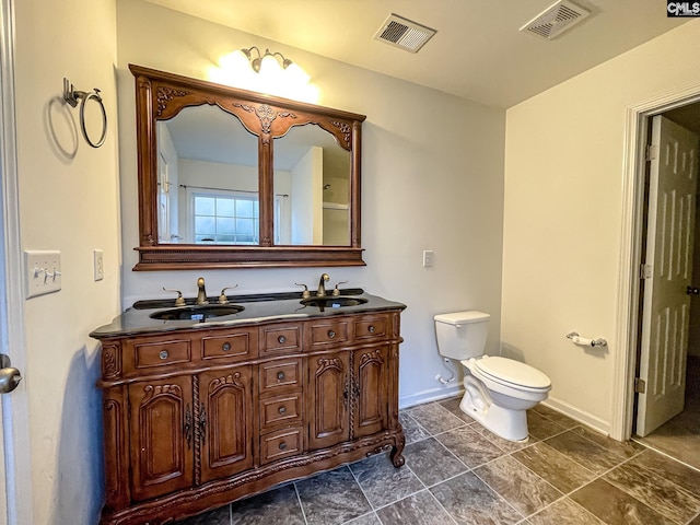 full bathroom featuring toilet, double vanity, visible vents, and a sink