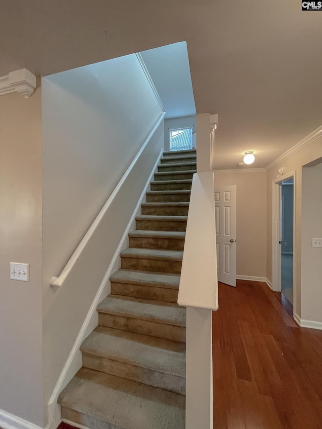 stairway featuring baseboards, wood finished floors, and ornamental molding