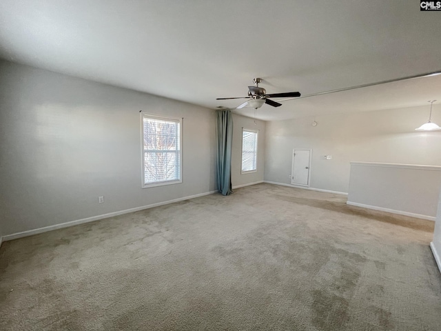 spare room featuring a ceiling fan, light carpet, and baseboards