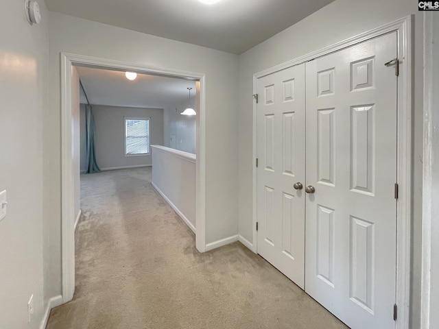 hallway with light colored carpet and baseboards