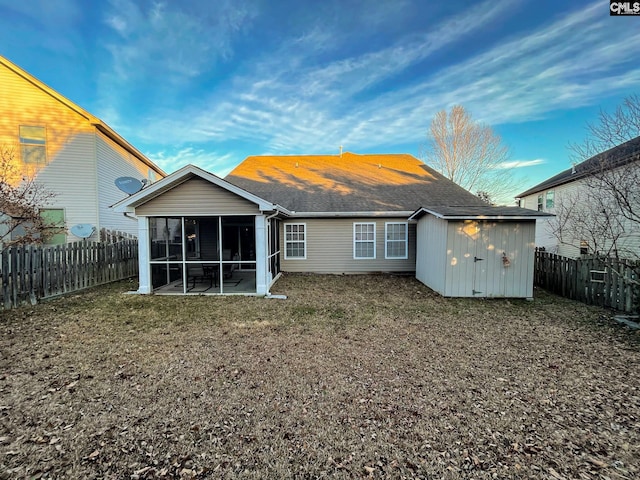 back of house featuring a storage unit, a lawn, a fenced backyard, and a sunroom