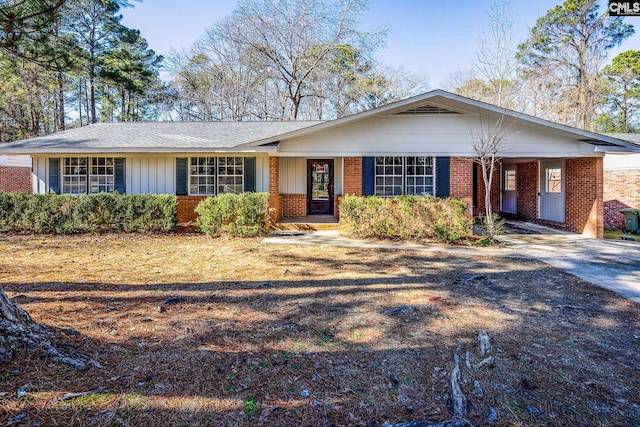 ranch-style house with a carport, concrete driveway, brick siding, and board and batten siding