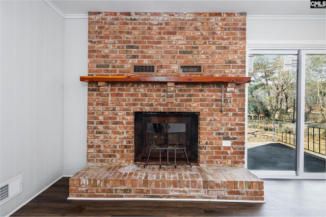 room details featuring a brick fireplace, visible vents, crown molding, and wood finished floors