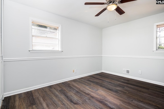 spare room with a ceiling fan, dark wood finished floors, visible vents, and baseboards