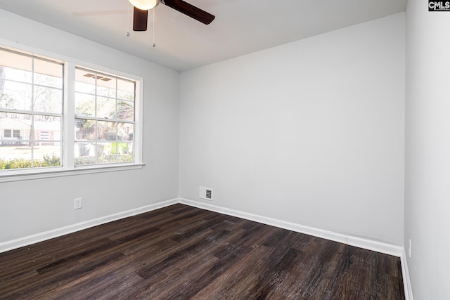 empty room featuring dark wood-style floors, a ceiling fan, visible vents, and baseboards