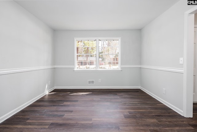 unfurnished room with dark wood finished floors, visible vents, and baseboards