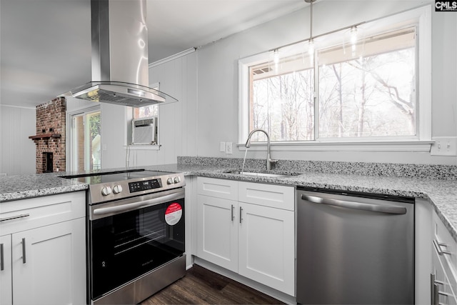 kitchen featuring appliances with stainless steel finishes, white cabinetry, a sink, island range hood, and light stone countertops