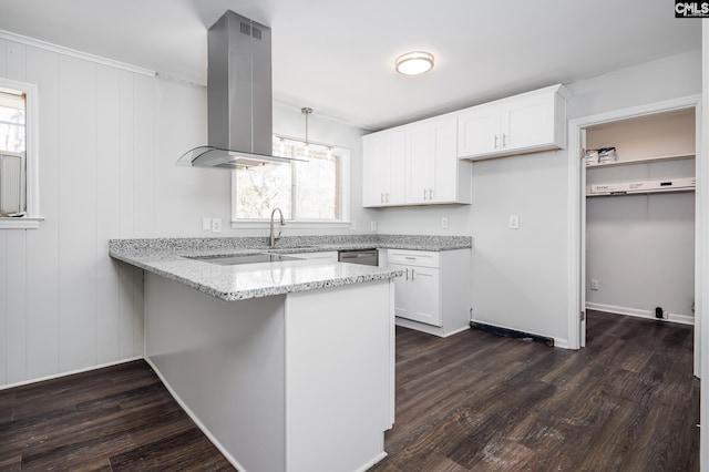 kitchen with light stone counters, island range hood, a peninsula, white cabinets, and hanging light fixtures