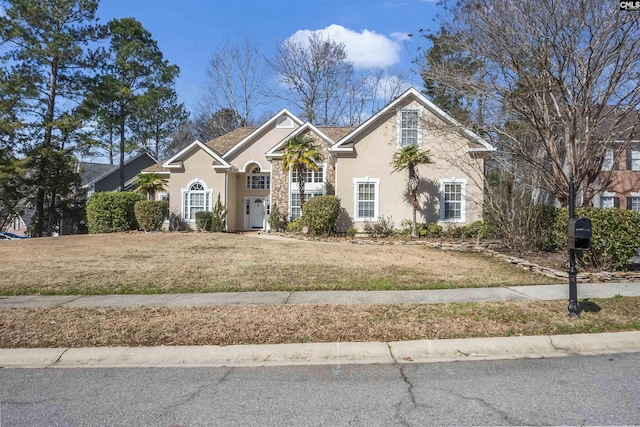 traditional home featuring a front yard and stucco siding