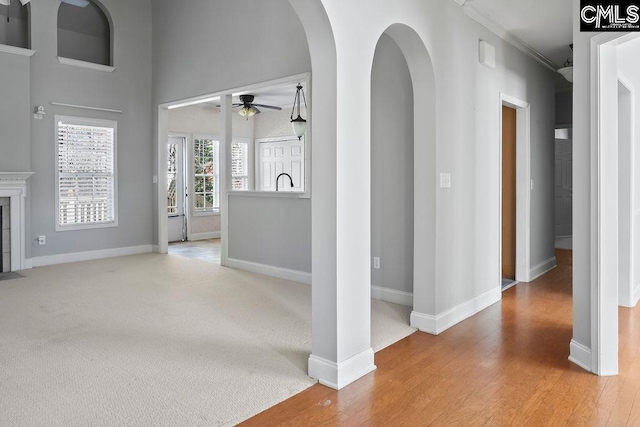 unfurnished living room featuring carpet floors, ceiling fan, baseboards, and wood finished floors