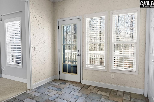 doorway with wallpapered walls, baseboards, and stone tile flooring