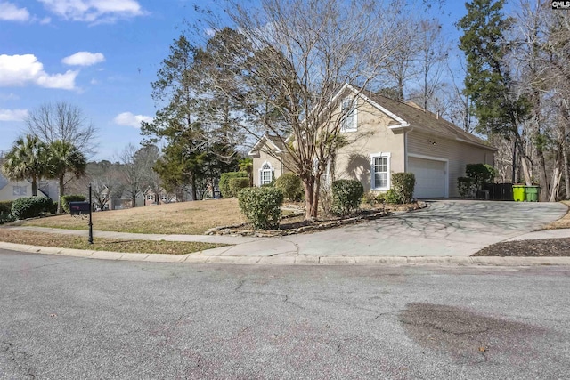 view of front facade with driveway, an attached garage, and stucco siding