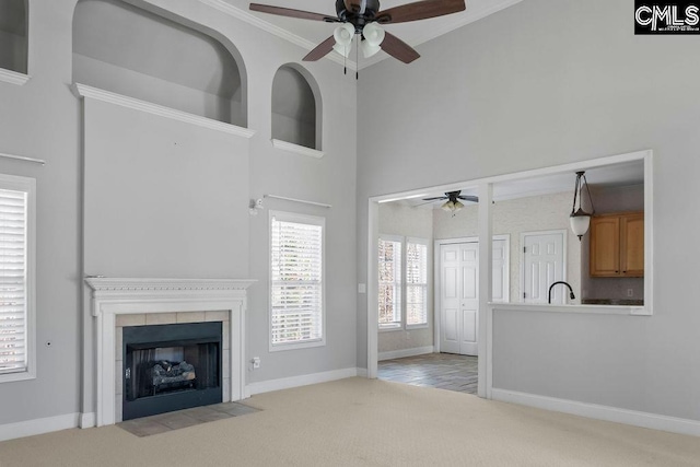 unfurnished living room featuring a tile fireplace, light carpet, and baseboards