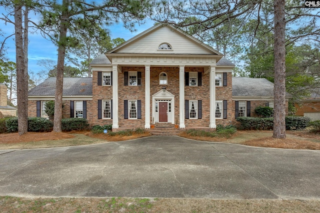 greek revival inspired property with a shingled roof and brick siding