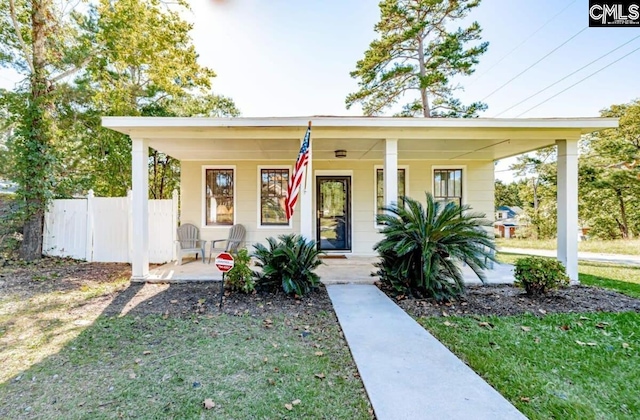 view of front of home featuring a front yard, covered porch, and fence