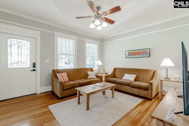 living area with a healthy amount of sunlight, light wood-style floors, baseboards, and crown molding