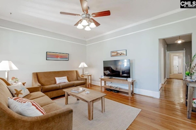 living area with ornamental molding, a ceiling fan, baseboards, and wood finished floors