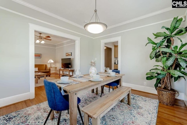 dining room with baseboards, crown molding, and light wood finished floors