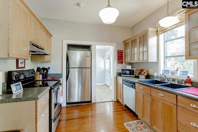 kitchen with dark countertops, glass insert cabinets, stainless steel appliances, and pendant lighting