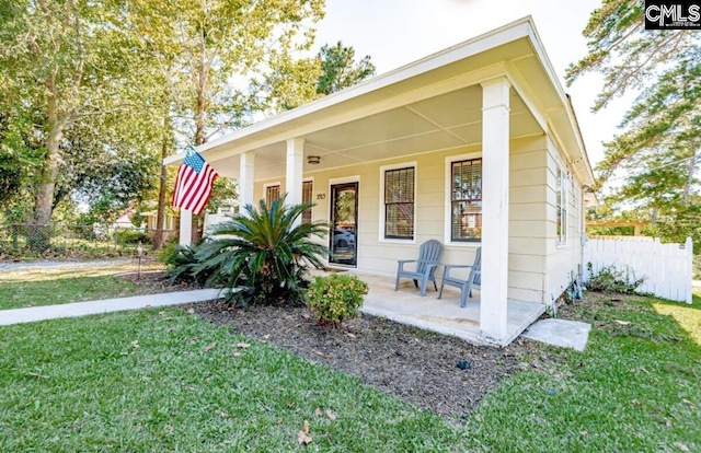 view of front of home with a porch, a front yard, and fence