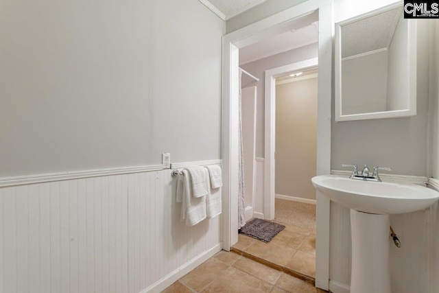 bathroom with a sink, wainscoting, and tile patterned flooring