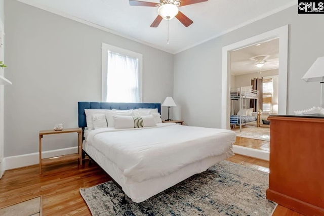 bedroom featuring ornamental molding, multiple windows, baseboards, and wood finished floors