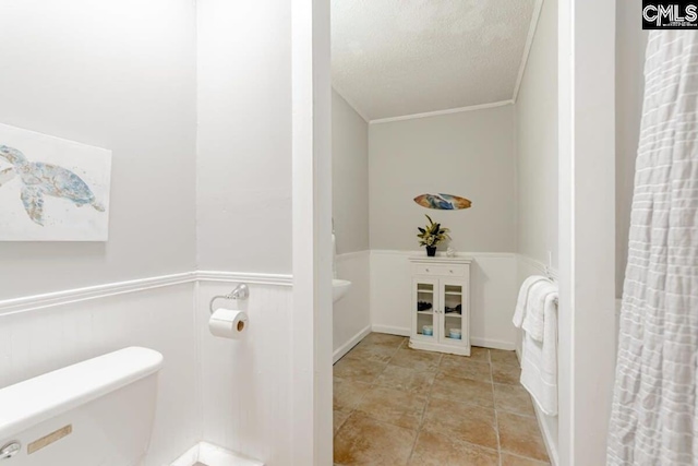 bathroom featuring wainscoting, a textured ceiling, and toilet