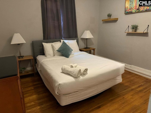 bedroom with dark wood-type flooring and baseboards