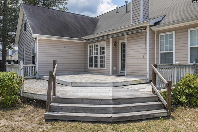 back of house featuring a deck, roof with shingles, and a chimney