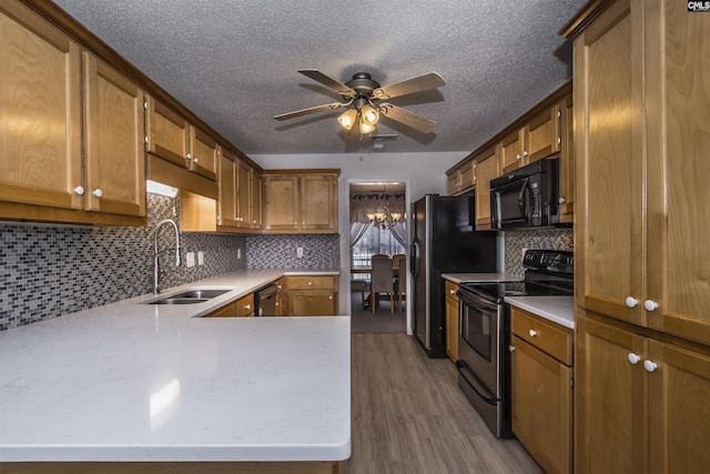 kitchen featuring brown cabinetry, electric stove, light countertops, black microwave, and a sink