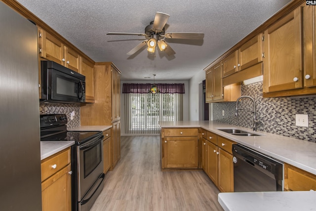 kitchen featuring brown cabinetry, light countertops, black appliances, pendant lighting, and a sink