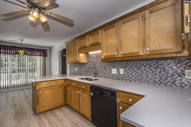 kitchen featuring a peninsula, black dishwasher, light countertops, and a sink