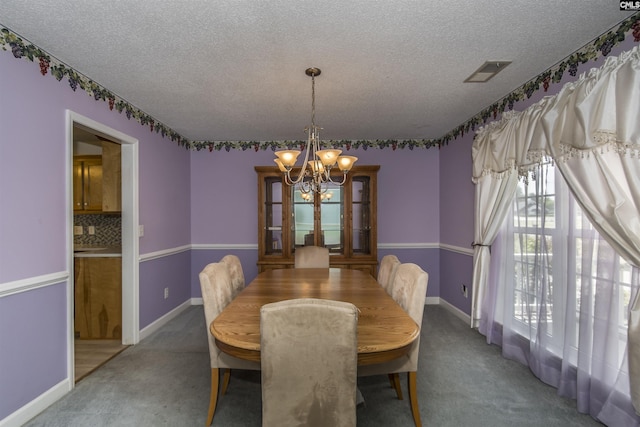 dining space featuring a chandelier, carpet floors, a textured ceiling, and visible vents