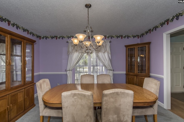 dining space featuring baseboards, a chandelier, a textured ceiling, and light colored carpet